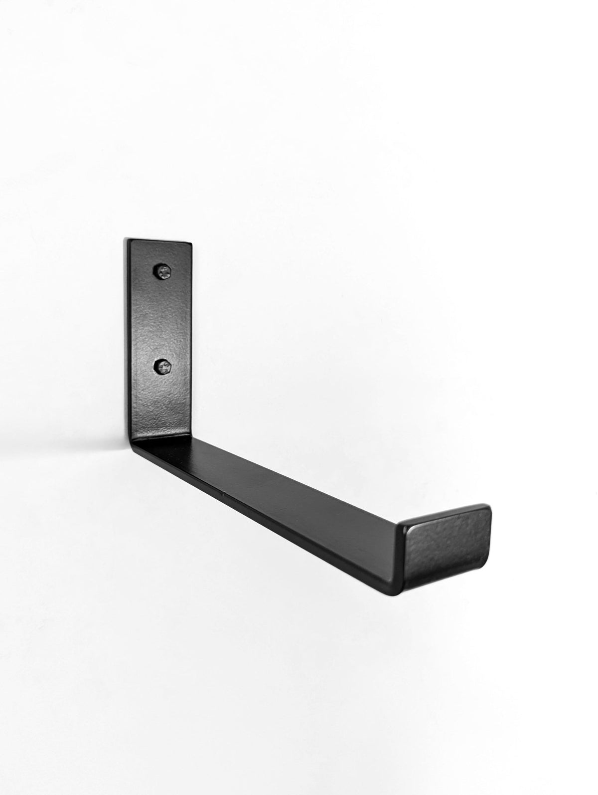 Metal J bracket installed into a white wall, it has a J hook design with a front lip to hold wood shelf