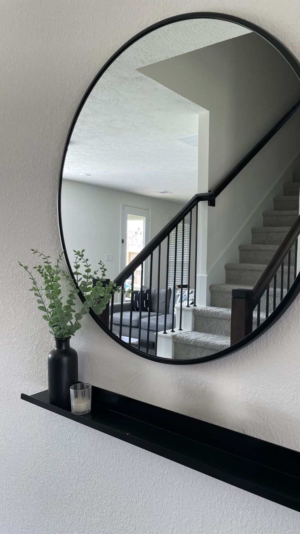 entryway with black ledge shelf and round mirror