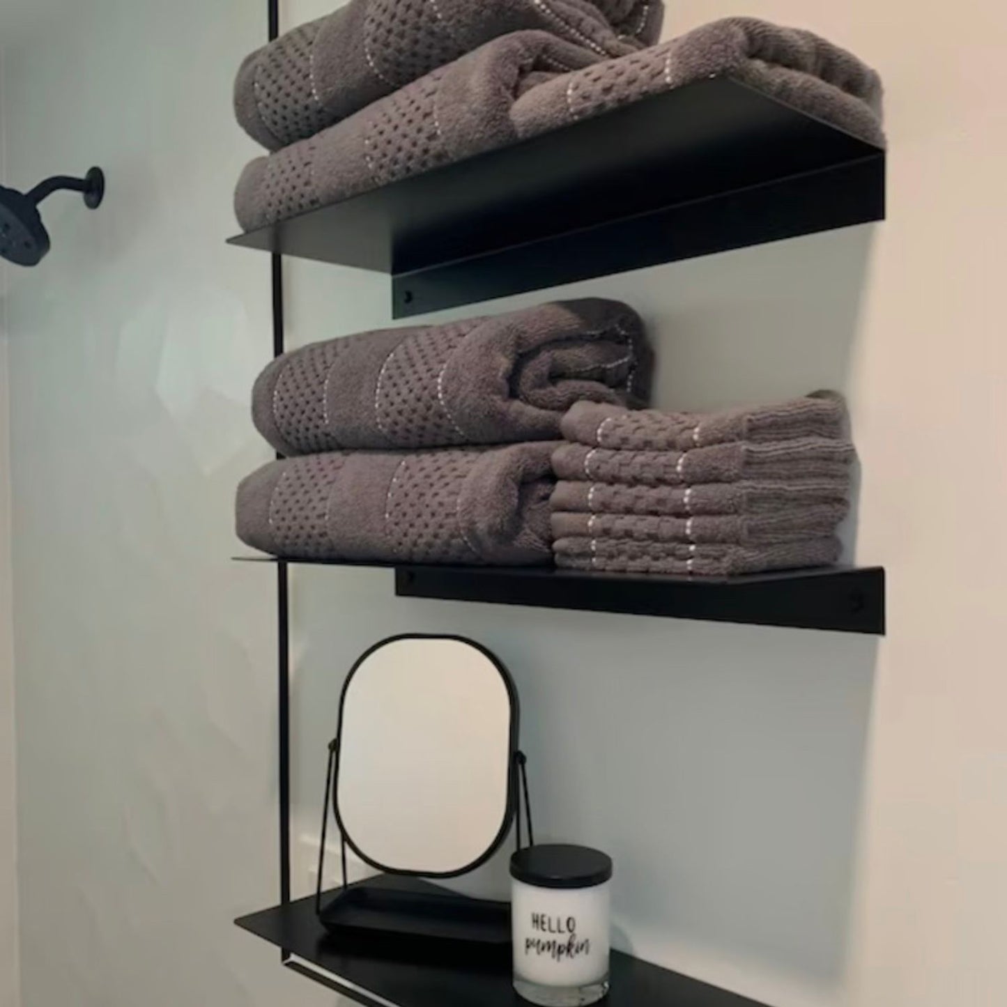 two black shelves mounted on wall with bathroom towels