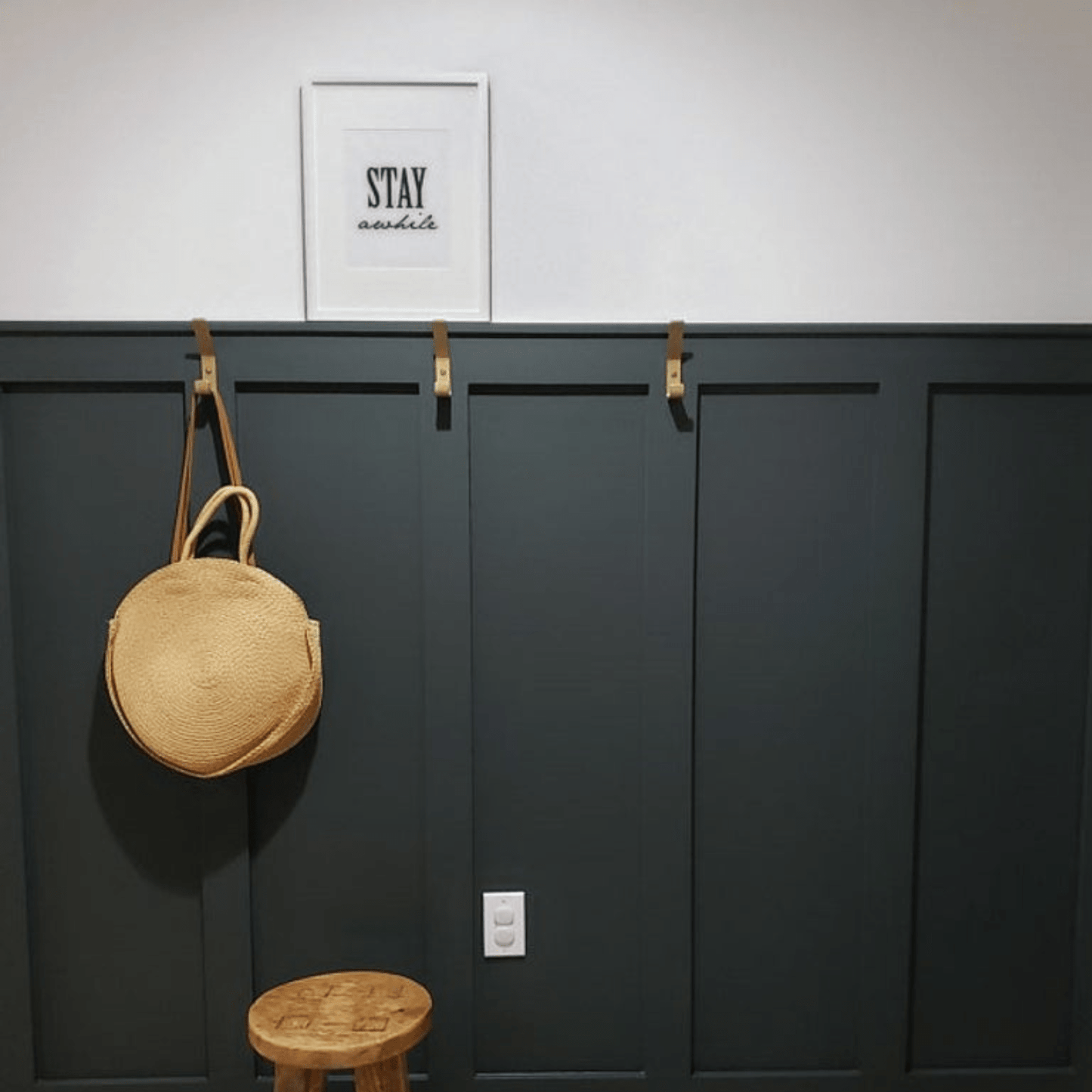 black entryway wall with brass wall hooks