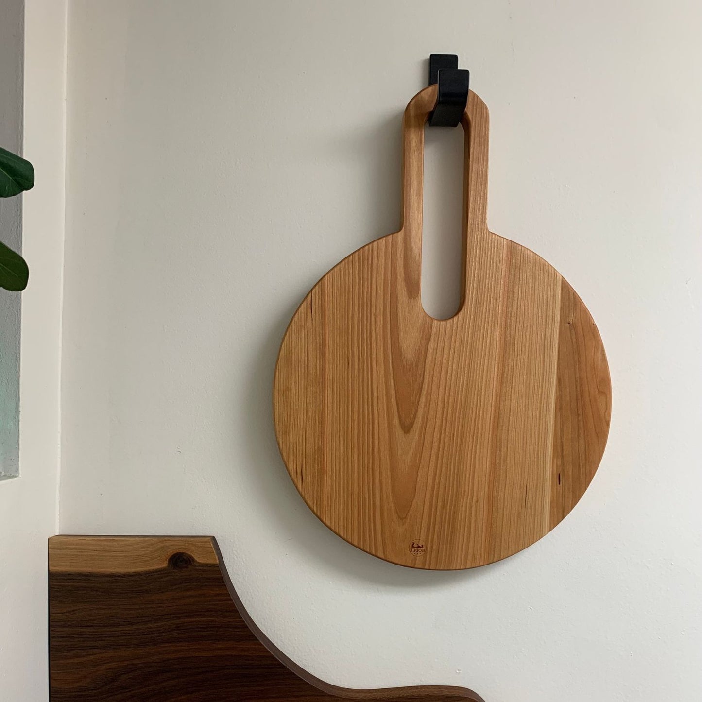 round cutting board hanging on wall with metal hook