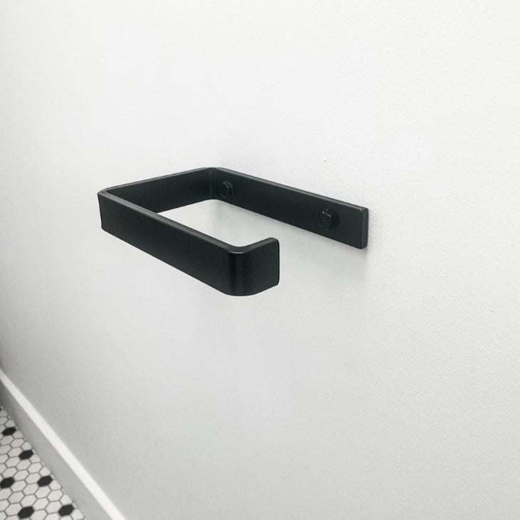 black toilet paper holder mounted on white wall