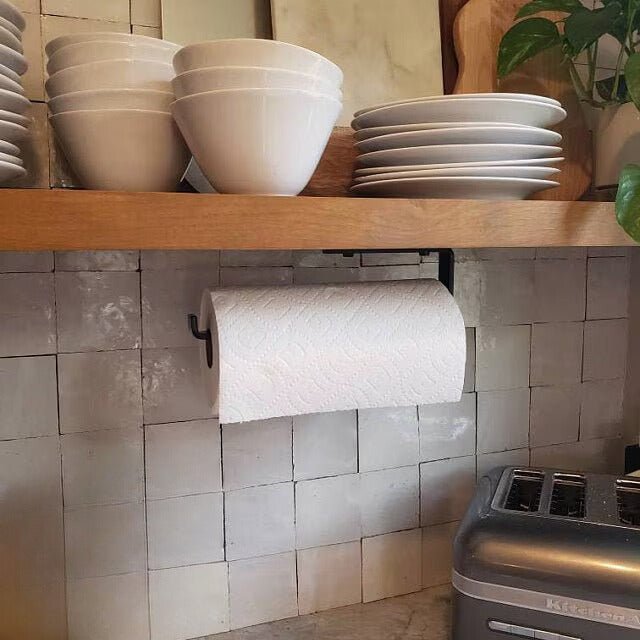 Black Paper Towel dispenser with paper towel roll installed under wood shelf in kitchen with gray tile backsplash
