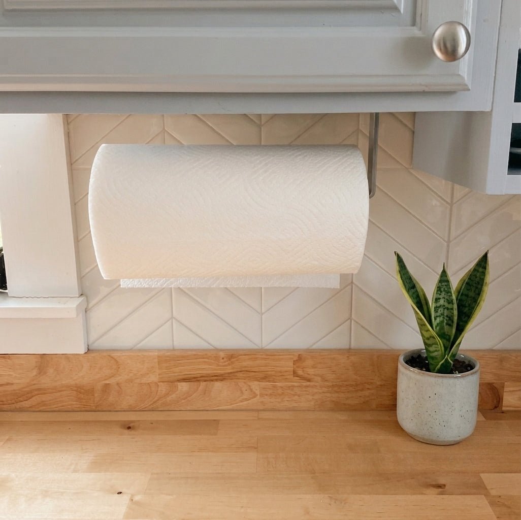 kitchen with silver paper towel holder mounted under gray cabinets. There is white backsplash and a wood countertop.