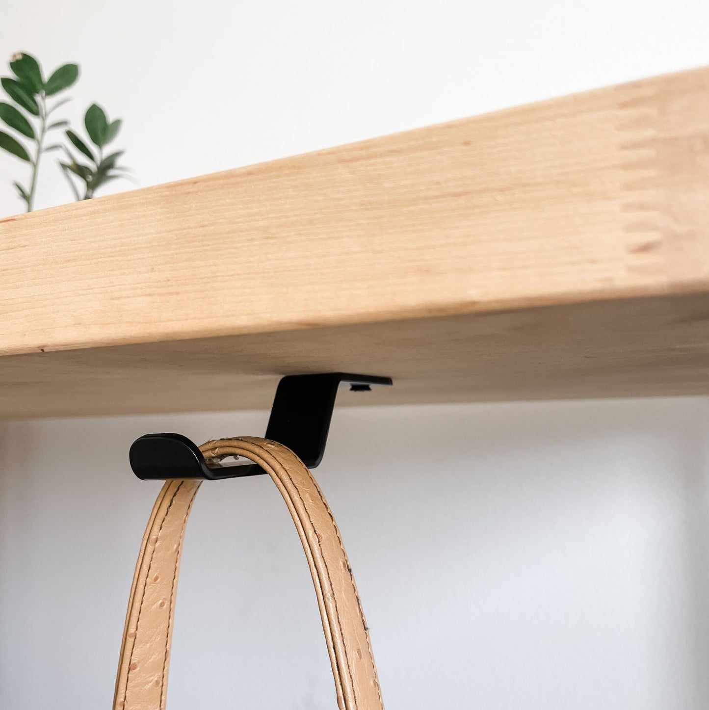 wood table with black purse hook installed underneath
