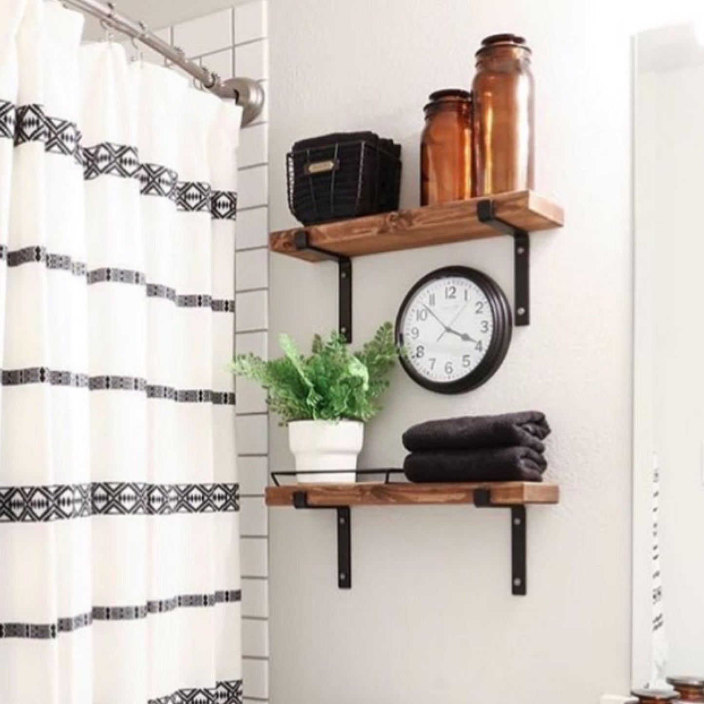 Two bathroom wood shelves with black shelf brackets and decor