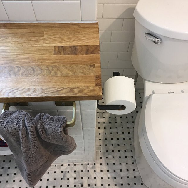 black metal tissue paper dispenser on cabinet next to toilet