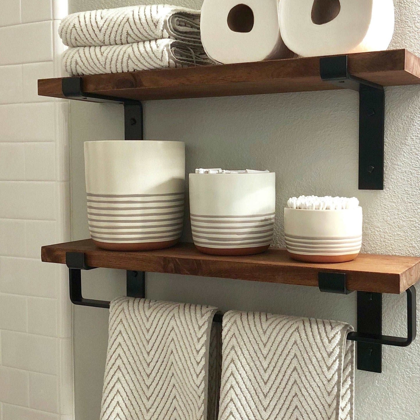 black bathroom towel bar under wood shelf with towels