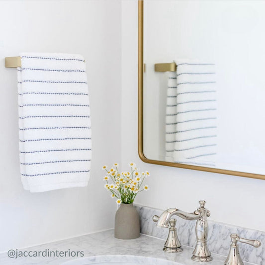 White bathroom with brass hardware including towel bar and mirror