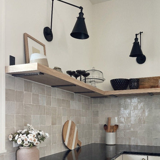 Modern kitchen with one shelf installed above tile backsplash with black L brackets there are sconces and decor