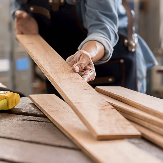 man holding a piece of dimensional lumber approximately 1 x 6" with other pieces of wood