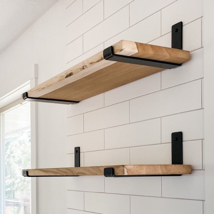 Two oak wood shelves mounted on white kitchen tile backsplash with black J style heavy duty shelf brackets