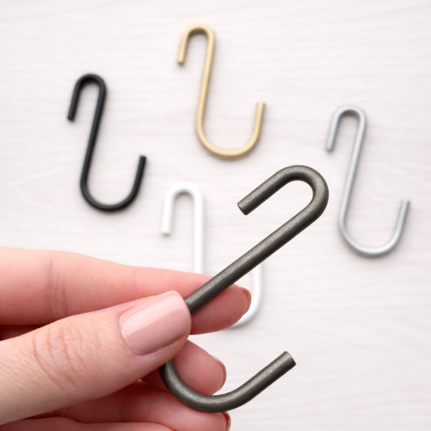 hand holding metal s hook with more hooks in background
