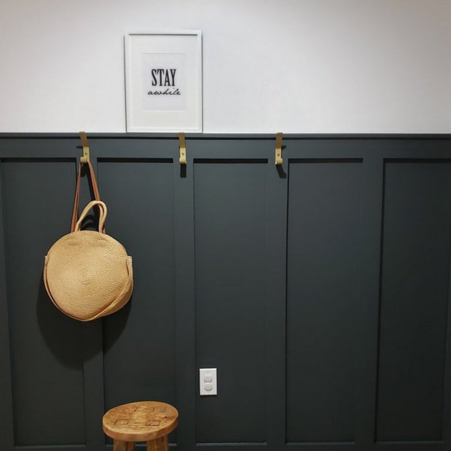 black entryway wall with brass hooks