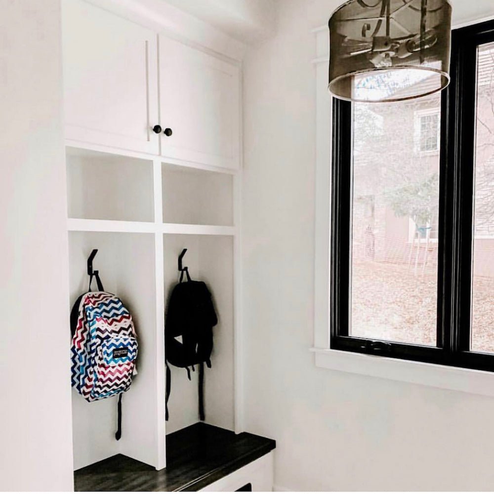 entryway with large white cabinet with black metal hooks installed onto mudroom cubby