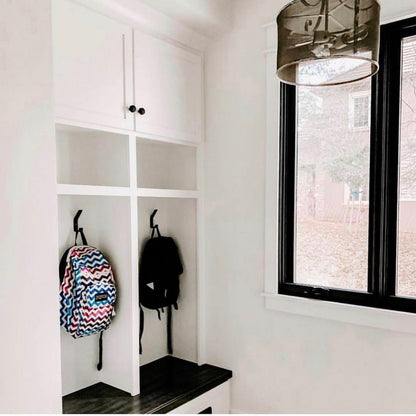 entryway with large white cabinet with black metal hooks installed onto mudroom cubby