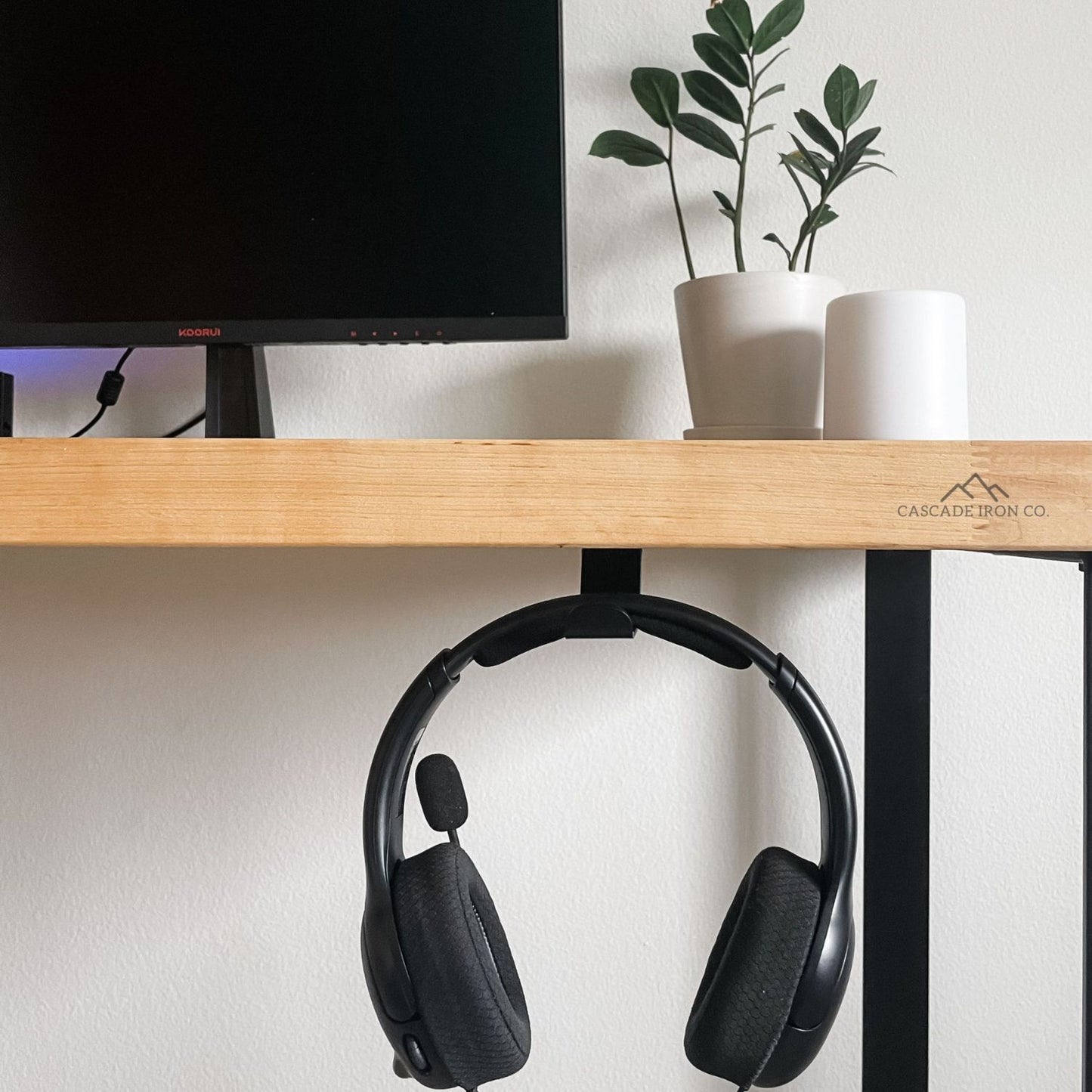 desk with headset hanging from hook