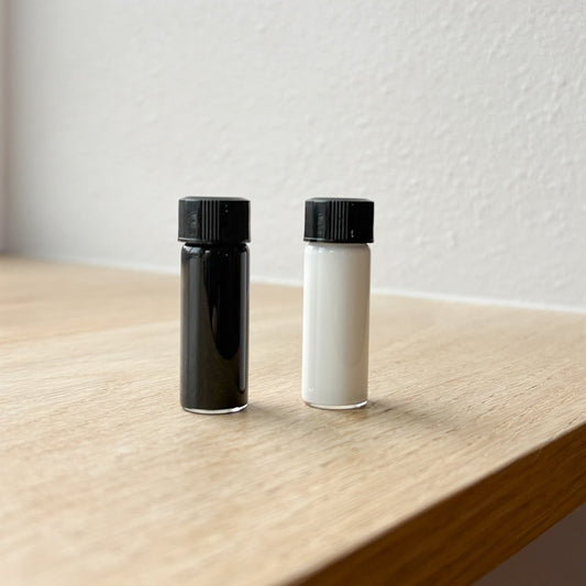 Two small glass jars with black lids on a wooden surface.