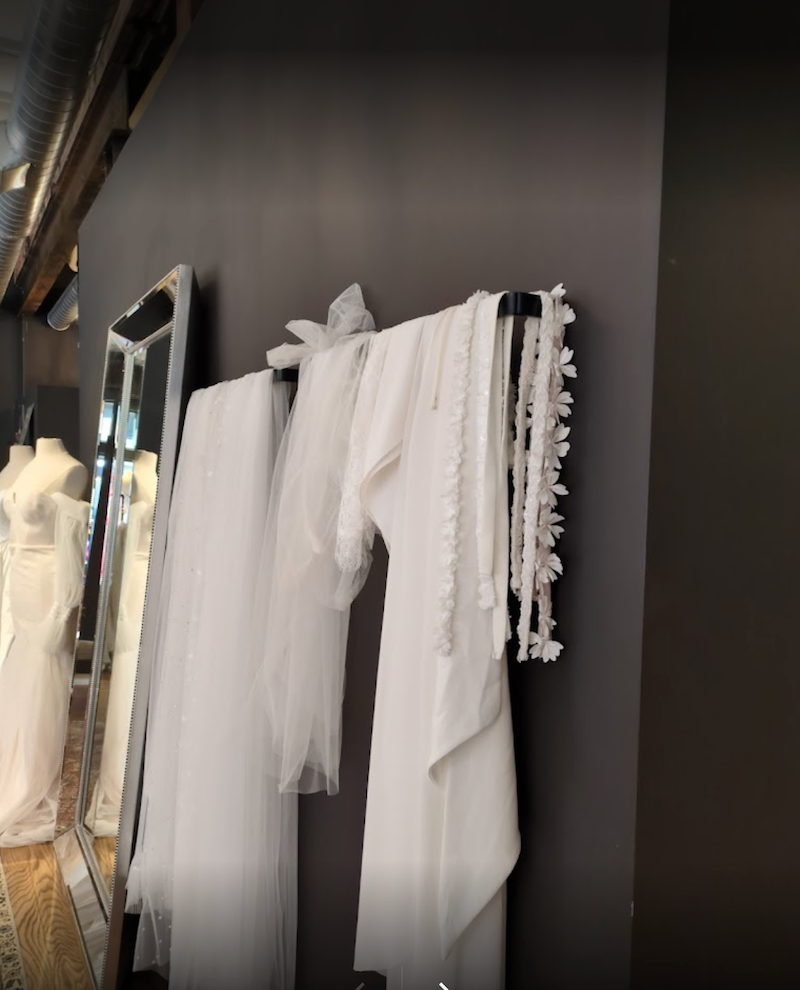 White lace garment hanging on a rack against a dark wall.