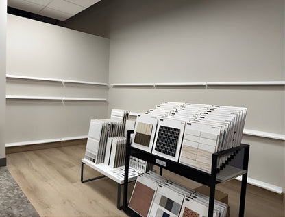 Design store with multiple floating wall mounted display ledges mounted on gray walls. There is also a  retail rack