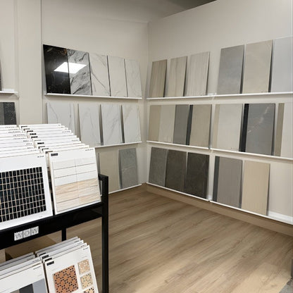 Interior design store with stone tiles displayed on three rows of white wall mounted metal shelf ledges.