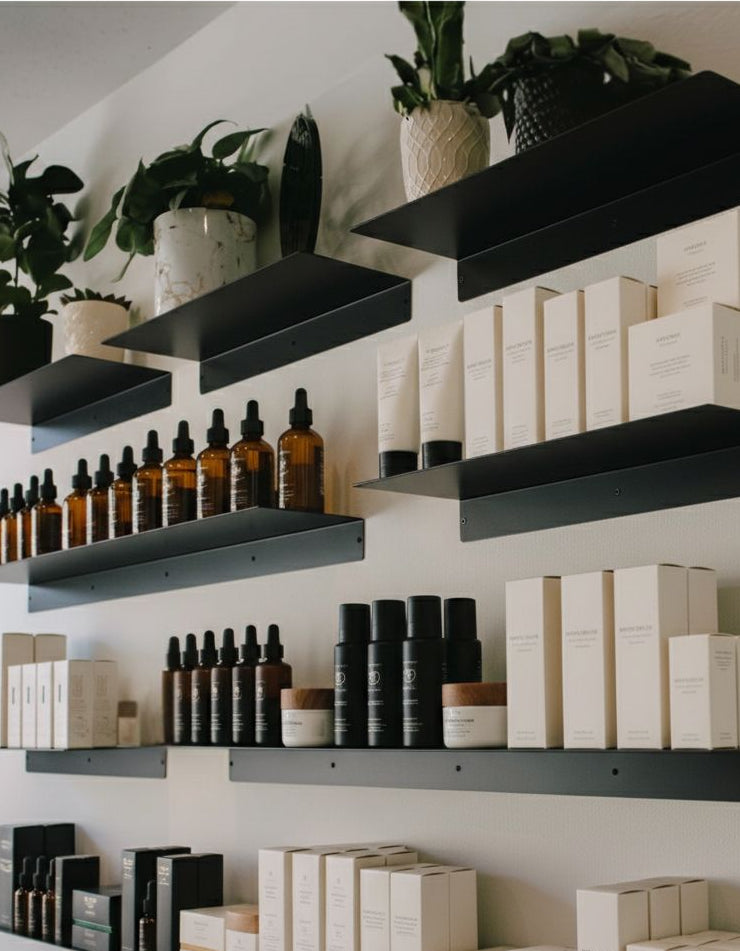 Metal Retail Display Shelves with skincare products and boxes in a well-lit room with plants.