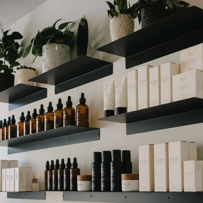 Black Metal Floating Retail Display Shelves installed on white wall with skincare products, bottles, and boxes