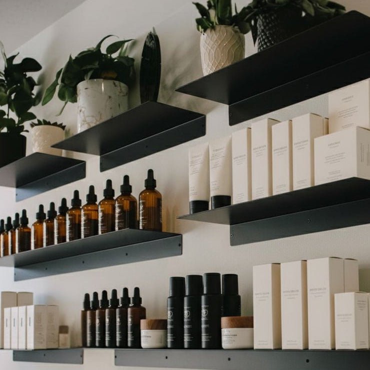 Black Metal Floating Retail Display Shelves installed on white wall with skincare products, bottles, and boxes