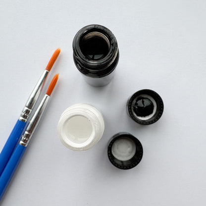 Set of small paint bottles and a brush on a white background