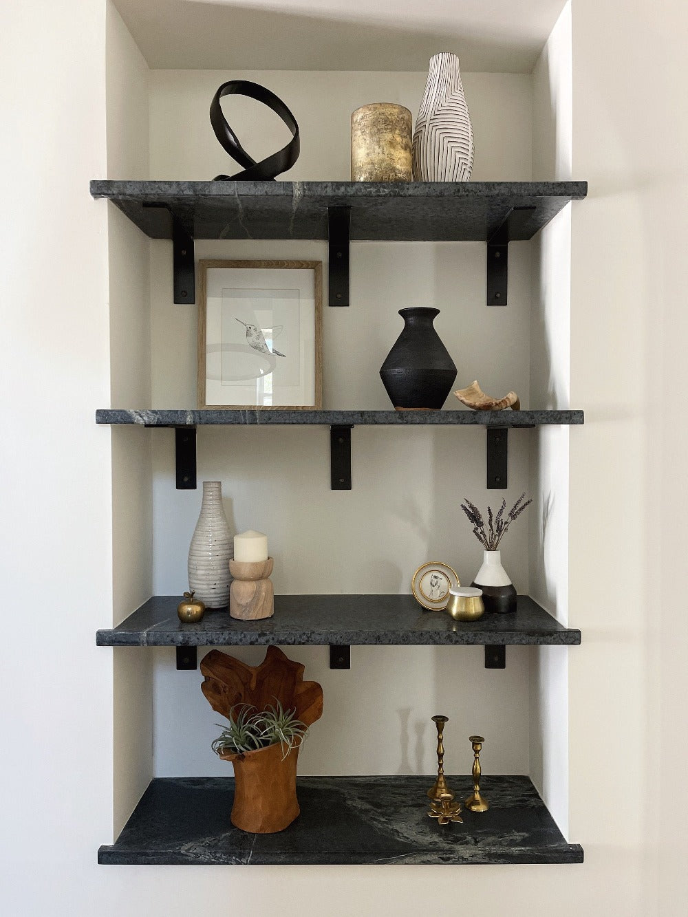 marble shelves with black brackets in wall nook